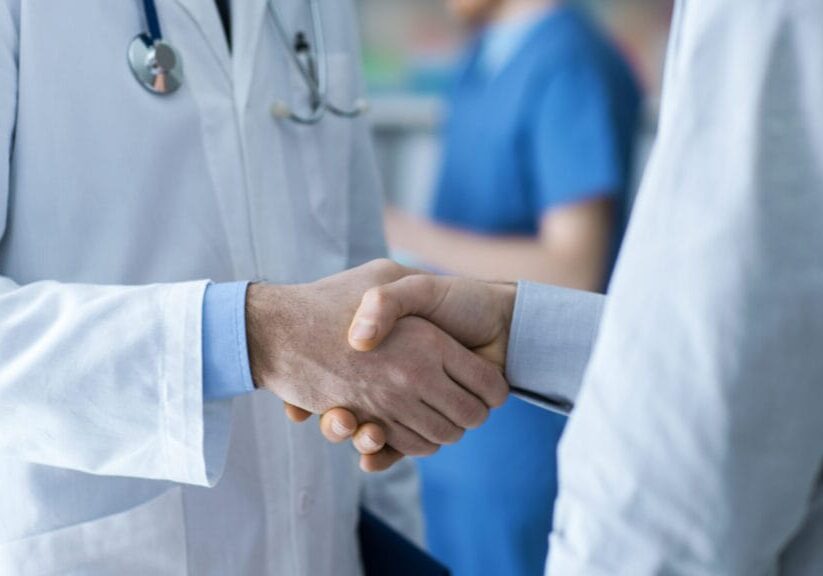 Doctor and patient shaking hands close up, healthcare and assistance concept